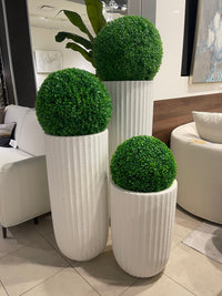 A set of three white, textured planters with stripes, each holding a green spherical plant.
