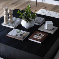 Decorative items on a dark coffee table including books, a vase with flowers, and candle holders.