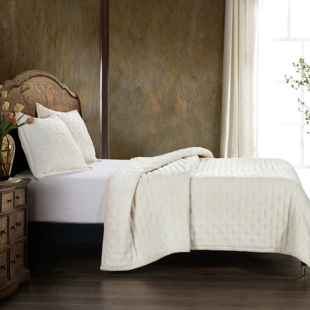 Bed with white bedding and quilt in a bedroom setting