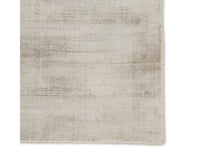 A light taupe area rug with a solid pattern, handwoven from 100% viscose.