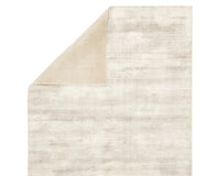 A light taupe area rug with a solid pattern, handwoven from 100% viscose.