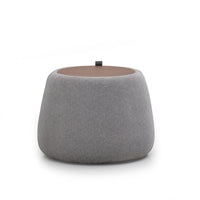 A round gray upholstered Roman ottoman with a cushioned top.